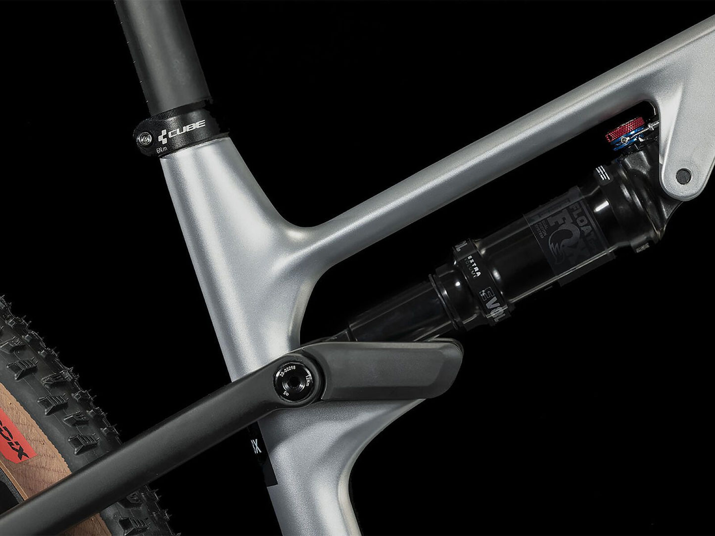 Nahaufnahme des silber-schwarzen Rahmens des Cube CUBE AMS ZERO99 C:68X Race 29. Hervorzuheben sind das hintere Federbein, ein Teil des Hinterradreifens und das silber-schwarze Carbon-Design vor schwarzem Hintergrund.