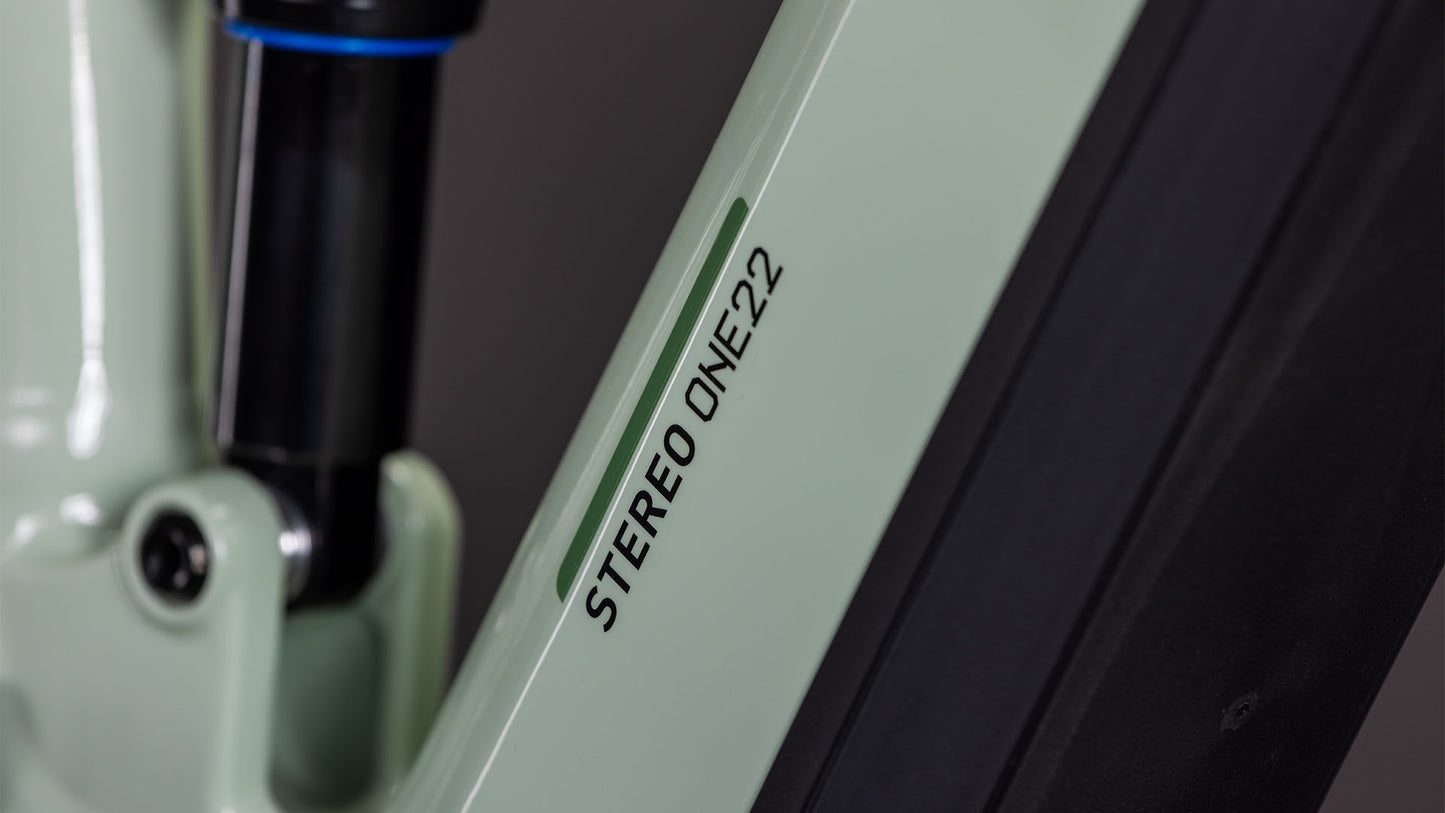 Nahaufnahme eines Cube Stereo Hybrid ONE22 Pro 800 steingrau-schwarzen 2026 Fahrradrahmens mit dem Schriftzug "STEREO ONE22" auf hellgrauen Rohren sowie Federung und CUBE Branding im Hintergrund.