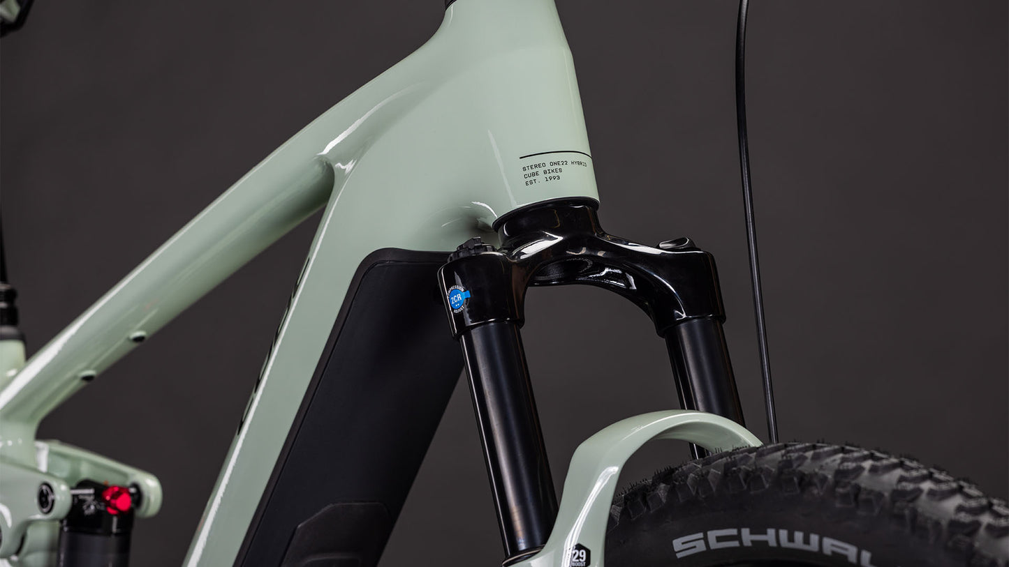 Nahaufnahme der CUBE Kinematik-Federgabel und des Reifens mit Schwalbe-Logo, mit einem Ausschnitt des CUBE Stereo Hybrid ONE22 Pro 800 stonegrey'n'black 2026 Rahmens und Bremszügen vor dunklem Hintergrund.