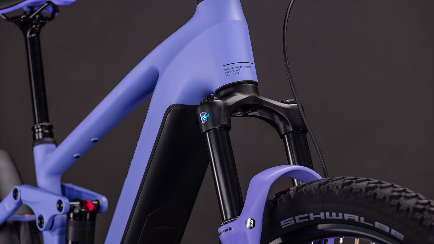 Die Nahaufnahme des CUBE Stereo Hybrid ONE22 Pro 800 lucidlilac'n'lime 2026 zeigt den mattvioletten Rahmen, die Federgabel und die schwarzen Komponenten mit einem Schwalbe-Reifen vor einem dunklen Hintergrund.