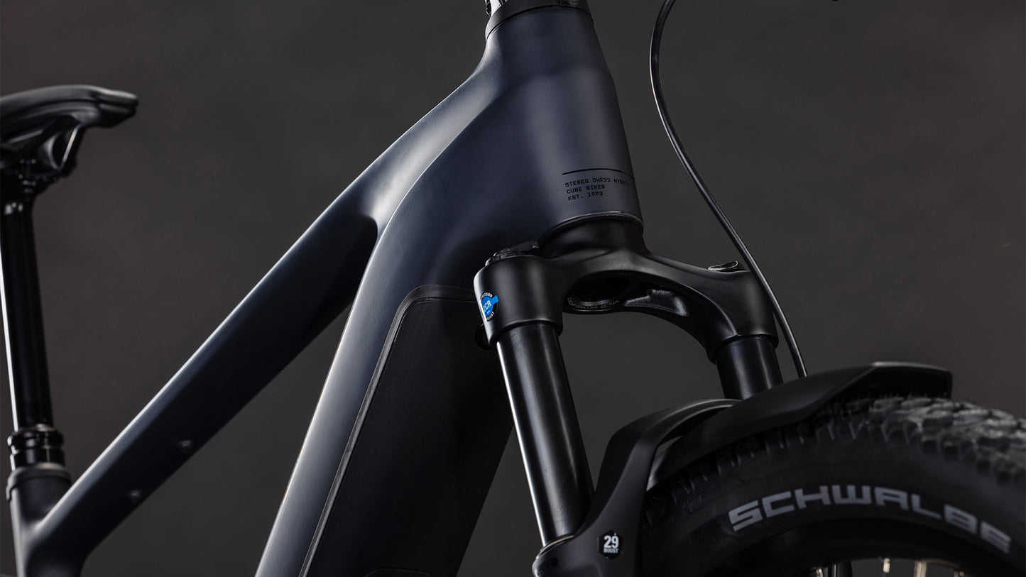 Nahaufnahme des Vorderrahmens und der Federgabel des mattschwarzen CUBE Stereo Hybrid ONE22 Pro 800 FE night'n'chrome 2026 mit Shimano-Scheibenbremsen und Schwalbe-Reifen vor einem dunklen Hintergrund.