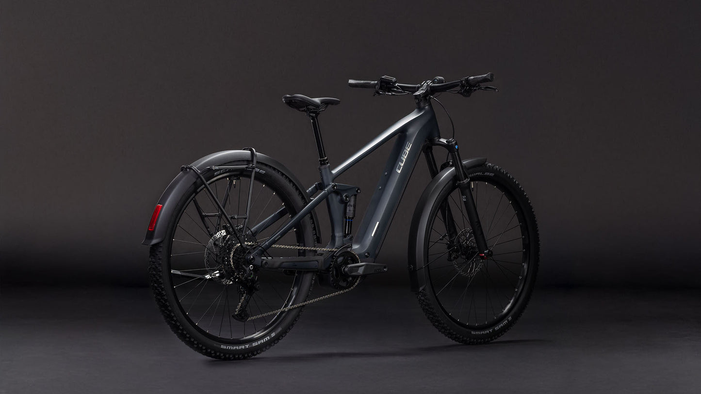 Das CUBE Stereo Hybrid ONE22 Pro 800 FE night'n'chrome 2026 verfügt über einen mattgrauen Rahmen, einen Bosch CX-Motor, eine Vorderradaufhängung, dicke Reifen, Scheibenbremsen und ein hinteres Schutzblech - und das alles vor einem dunklen Hintergrund.