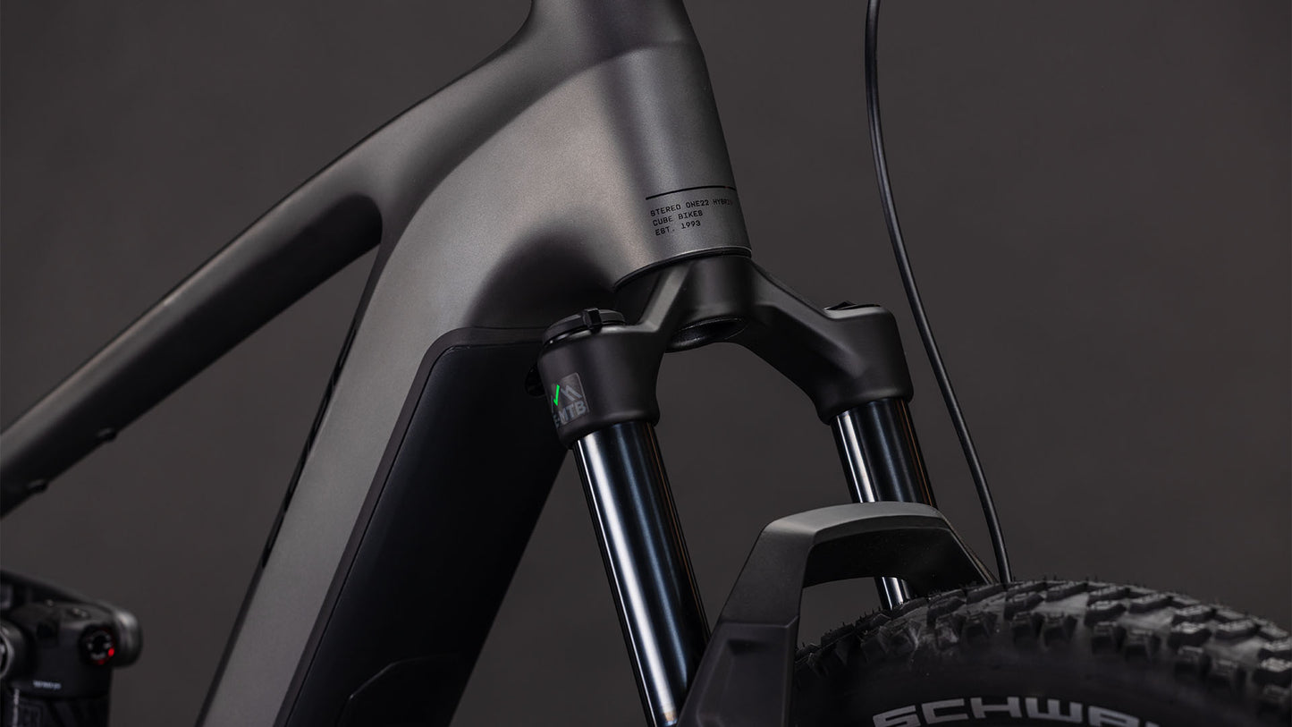 Nahaufnahme des mattschwarzen CUBE Stereo Hybrid ONE22 Race 800 slabgrey'n'chrome 2026-Rahmens und der Federgabel, mit Noppenreifen und Schwalbe-Branding sowie Shimano 12-fach XT-Schaltungsdetails vor dunklem Hintergrund.