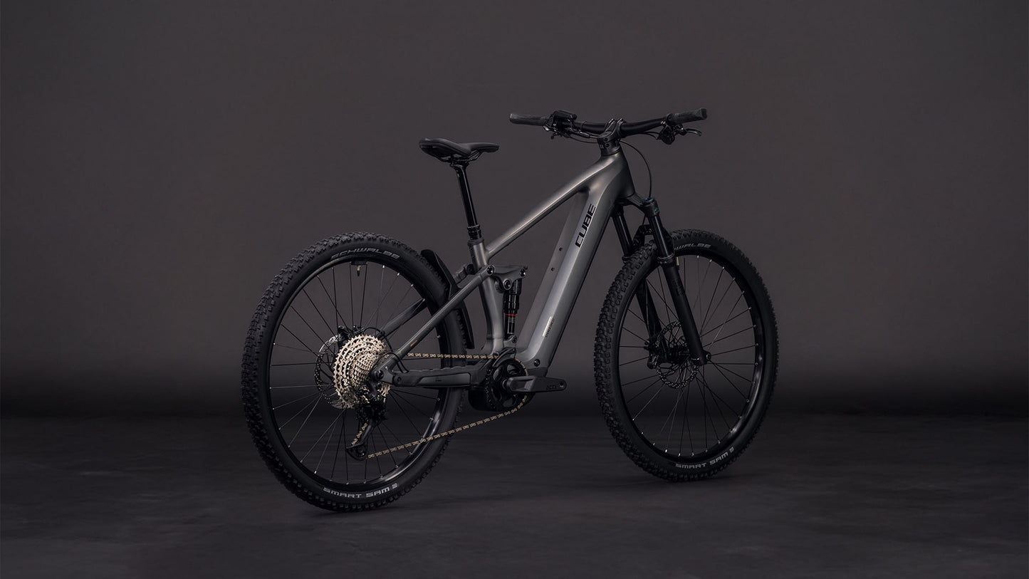 Das CUBE Stereo Hybrid ONE22 Race 800 slabgrey'n'chrome 2026, ein mattgraues E-Fully-Mountainbike mit Bosch CX-Motor und Shimano 12-Gang-XT-Schaltung, ist auf einem dunklen Hintergrund abgebildet, der seine dicken Reifen und den schlanken, vollgefederten Rahmen hervorhebt.
