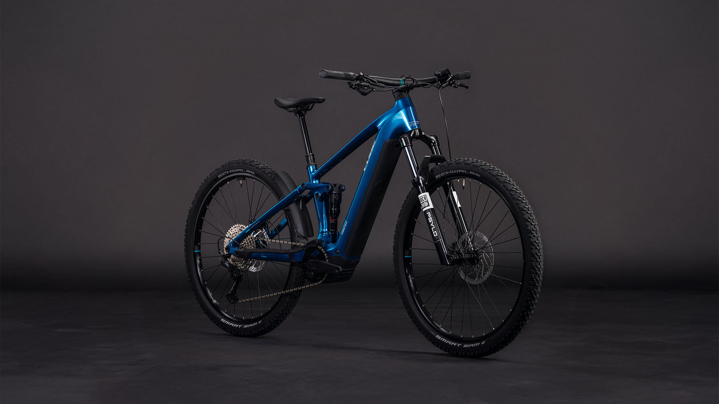 Das CUBE Stereo Hybrid ONE22 Race 800 electricblue'n'white 2026 E-Fully Mountainbike ist mit schwarzen Laufrädern und Reifen, Scheibenbremsen, einem Bosch CX-Motor und einer Shimano 12-fach XT-Schaltung ausgestattet und wird vor einem dunklen, einfarbigen Hintergrund gezeigt.