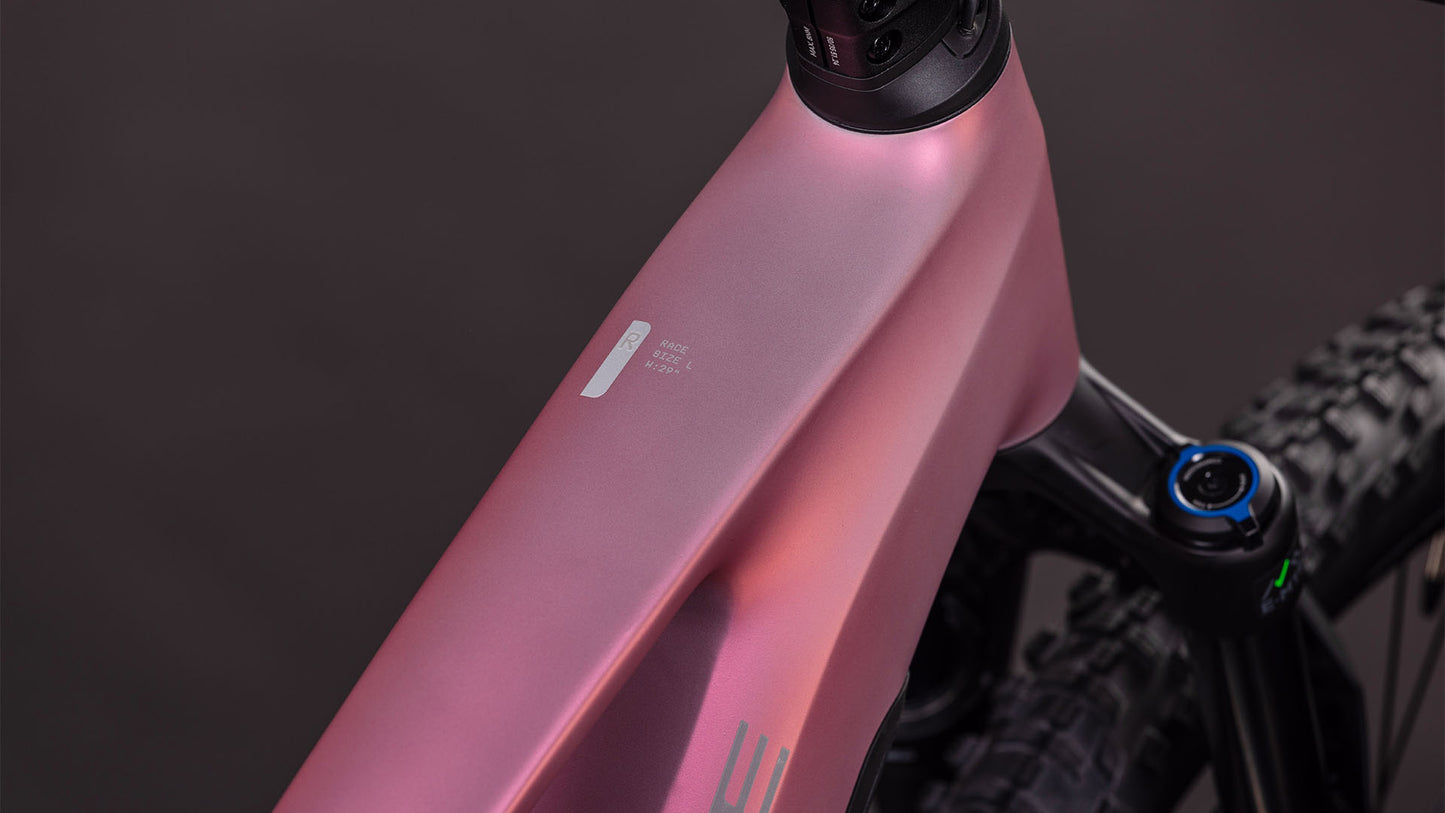 Nahaufnahme des Oberrohrs des CUBE Stereo Hybrid ONE22 Race 800 shiftblush'n'black 2026 E-Fully, das sich durch ein mattes rosa Finish, ein minimalistisches Design und einen glatten Rahmen mit sichtbarem Lenker und Vorderradaufhängung vor einem dunklen Hintergrund auszeichnet.