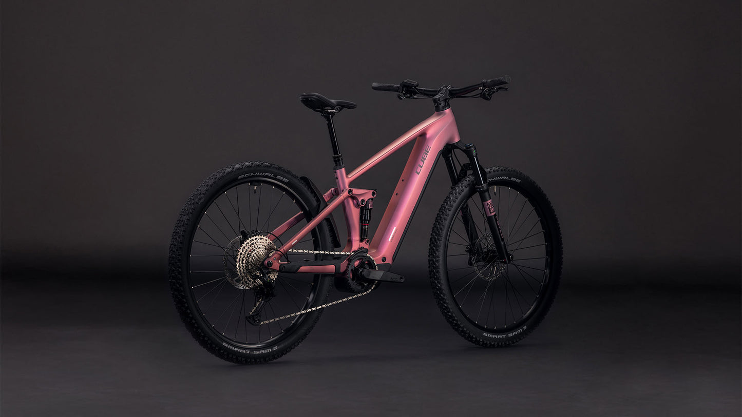 Das CUBE Stereo Hybrid ONE22 Race 800 shiftblush'n'black 2026 Mountainbike, ausgestattet mit dicken Stollenreifen, Bosch CX Motor, fortschrittlicher Federung und einem eleganten rosa-schwarzen Rahmen, wird vor einem dunklen Hintergrund präsentiert.