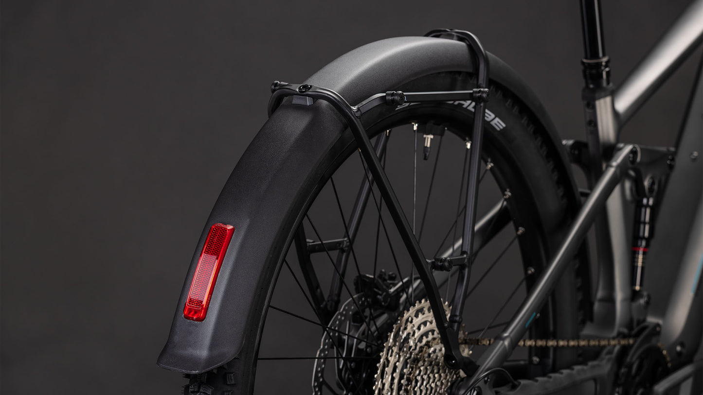 Nahaufnahme des Hinterrads eines CUBE Stereo Hybrid ONE22 Race 800 FE slabgrey'n'chrome 2026, das ein schwarzes Schutzblech mit rotem Reflektor, mehrere Gänge, Rahmendetails und den Bosch CX Motor vor einem dunklen Hintergrund zeigt.