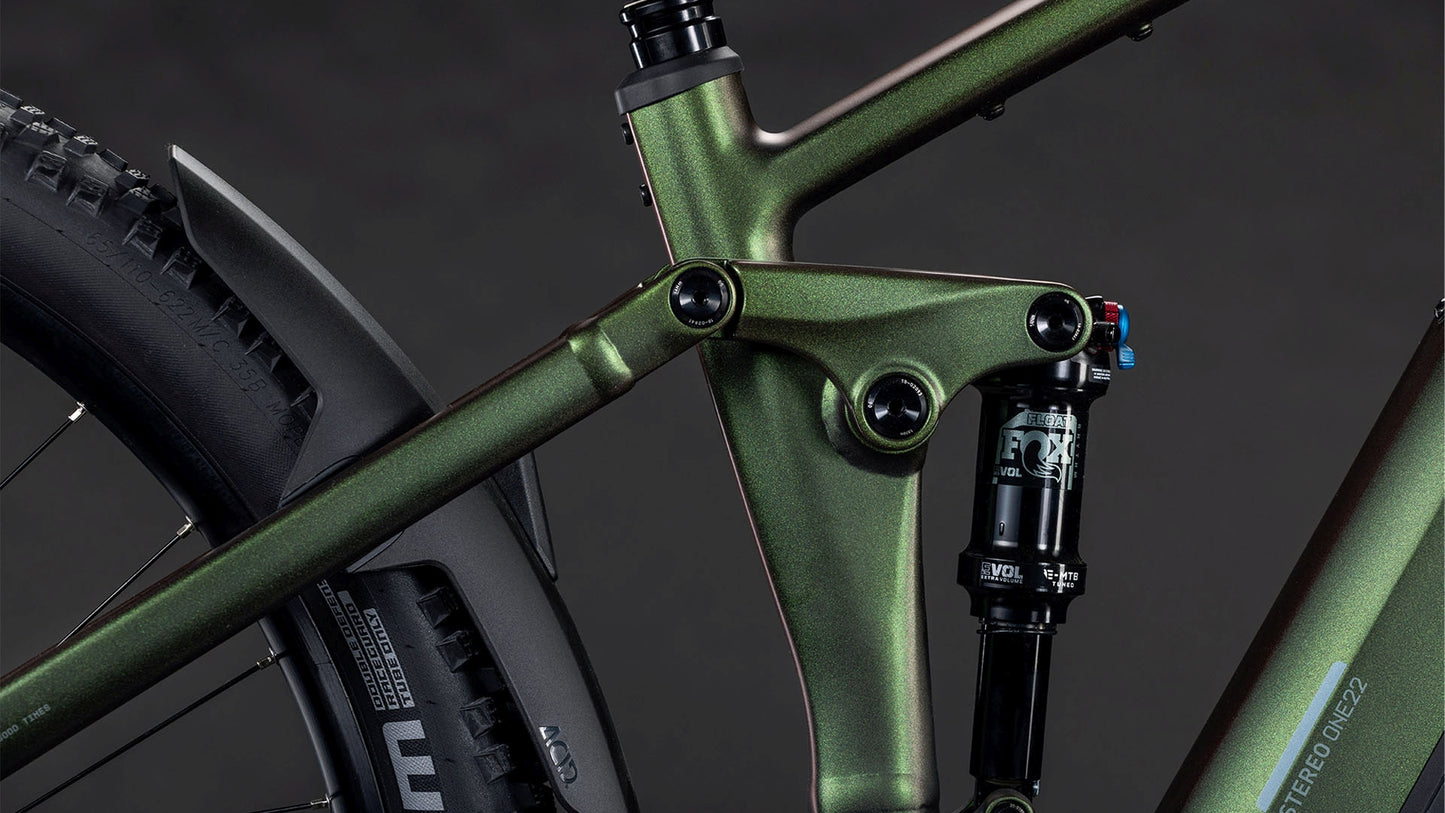 Nahaufnahme des CUBE Stereo Hybrid ONE22 SLX 800 stellar'n'green 2026 E-Fully Mountainbike-Rahmens mit Hervorhebung der Hinterradfederung, des Sitzrohrs, des Hinterradreifens und der Shimano XT Schaltung vor einem dunklen Hintergrund.