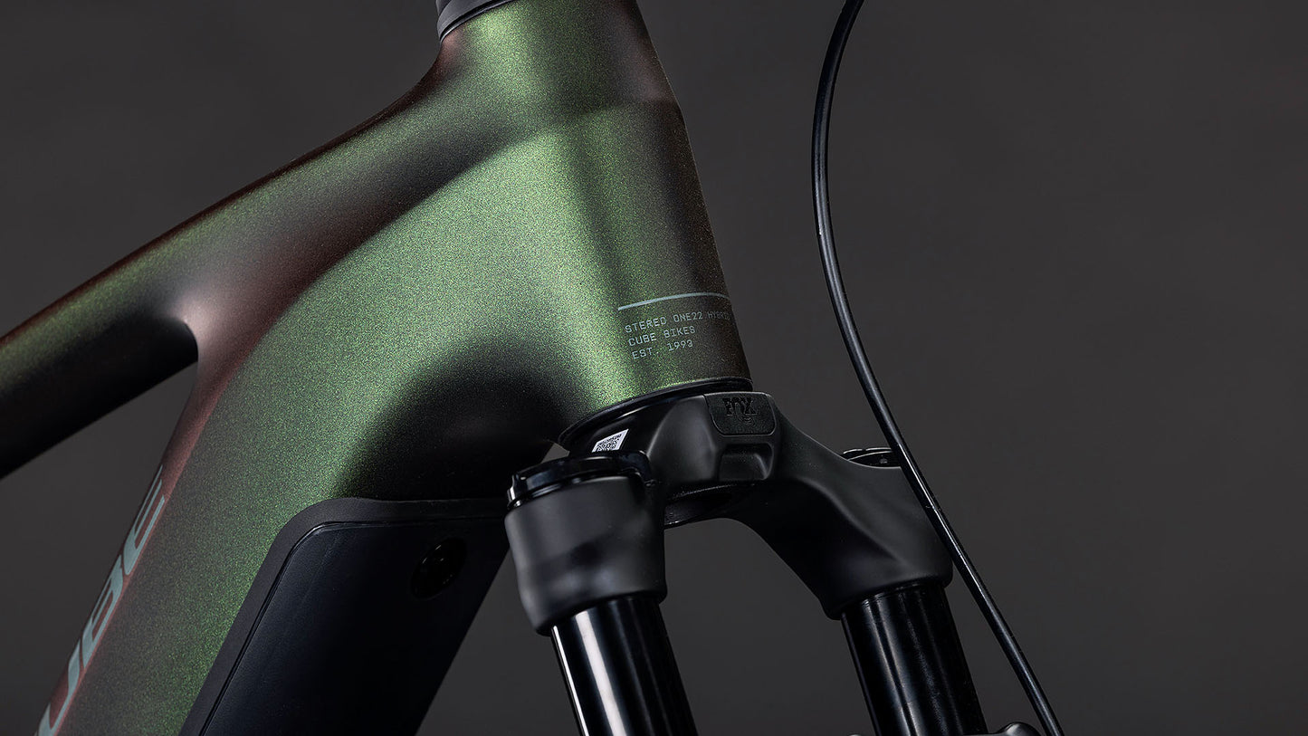 Nahaufnahme des Vorderrahmens und der Federgabel des CUBE Stereo Hybrid ONE22 SLX 800 stellar'n'green 2026, die das grüne Metallic-Finish, das schlanke E-Fully-Design und den fortschrittlichen Bosch CX-Antrieb vor einem dunklen Hintergrund zeigt.