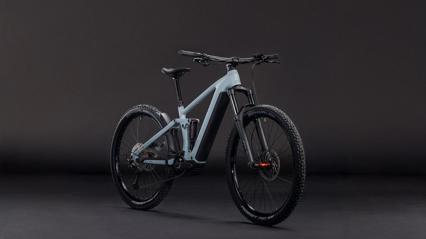Das CUBE Stereo Hybrid ONE44 Pro 800 vulcan'n'orange 2026 Mountainbike mit dicken Reifen, Vorderradaufhängung und Shimano XT Schaltung ist vor einem dunklen Hintergrund abgebildet, der so angewinkelt ist, dass die Front und die linke Seite zu sehen sind.