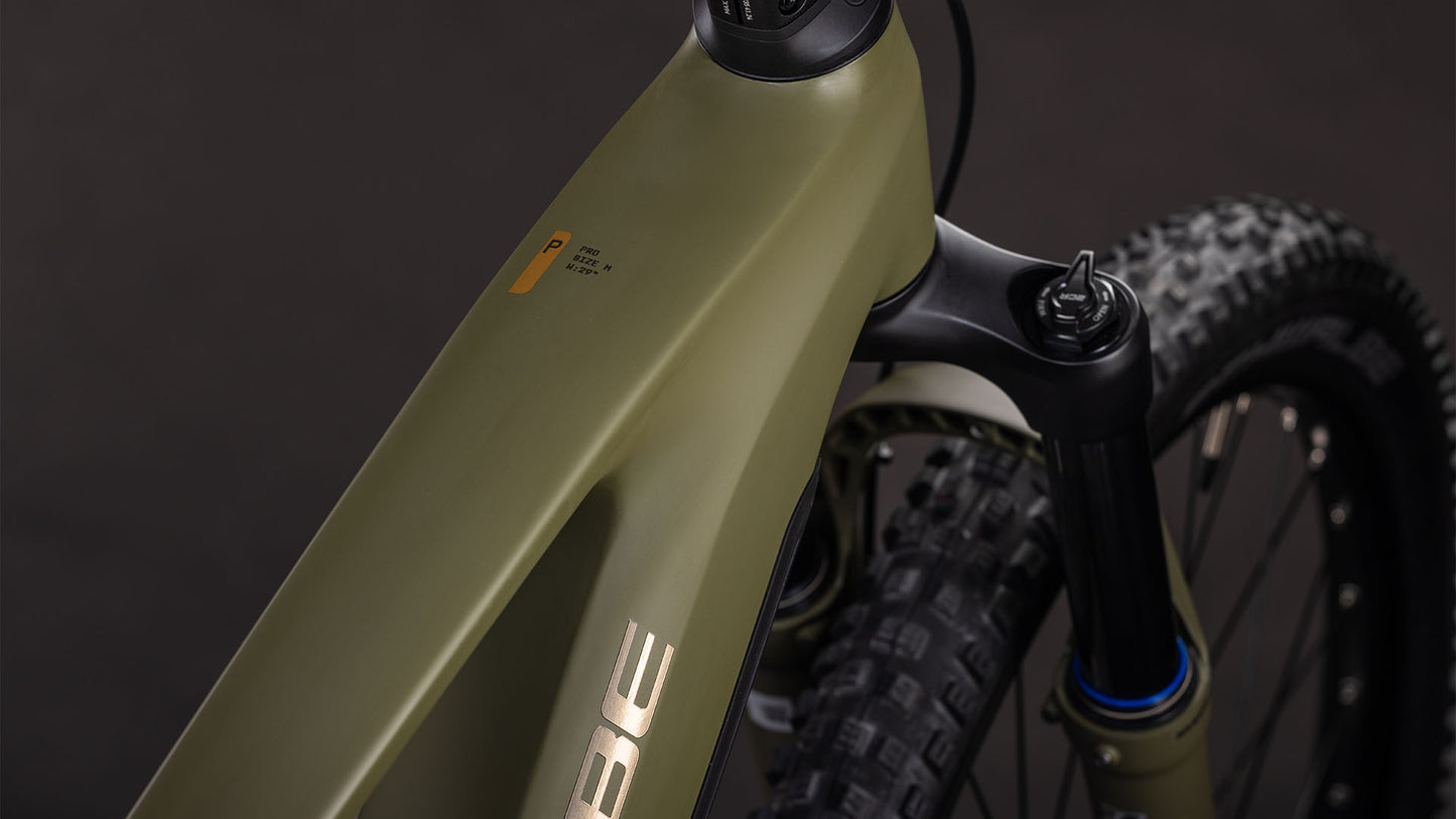Nahaufnahme des CUBE Stereo Hybrid ONE44 Pro 800 dustyolive'n'gold 2026, die das Oberrohr, die Federgabel, einen Teil des Lenkers und den knorrigen Vorderreifen vor einem dunklen Hintergrund hervorhebt.