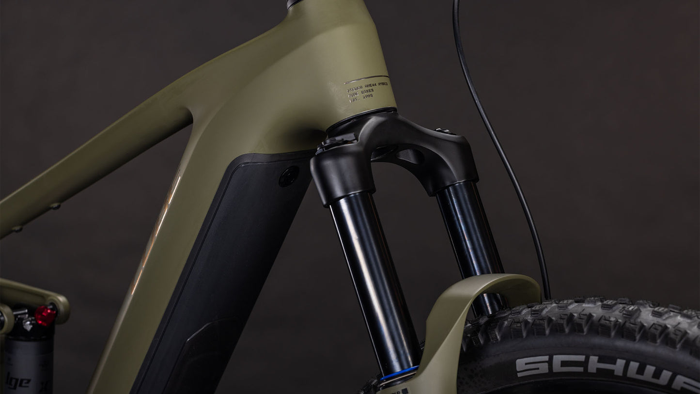 Nahaufnahme der vorderen Federgabel und des Reifens des CUBE Stereo Hybrid ONE44 Pro 800 dustyolive'n'gold 2026, die den mattgrünen Rahmen, die detaillierten Komponenten und den Bosch CX Motor vor einem dunklen Hintergrund hervorheben.