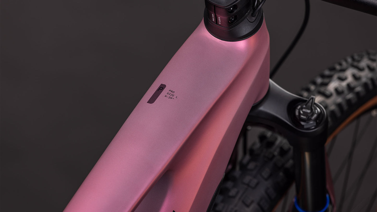Nahaufnahme des CUBE Stereo Hybrid ONE44 Pro 800 shiftblush'n'raisin 2026 Rahmens, die das Oberrohr, die Federgabel und ein kleines Display zeigt. Ausgestattet mit Bosch CX-Motor; der Hintergrund ist dunkel und unscharf.