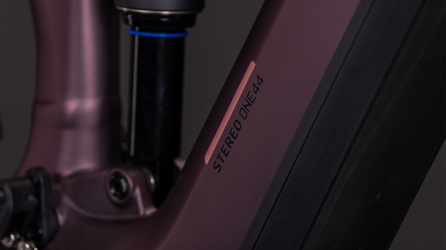 Nahaufnahme des CUBE Stereo Hybrid ONE44 Pro 800 in shiftblush'n'raisin, mit dem STEREO ONE44 in Schwarz auf dem mattvioletten Rahmen, mit sichtbarer Federung, Bosch CX-Motor und anderen Details.