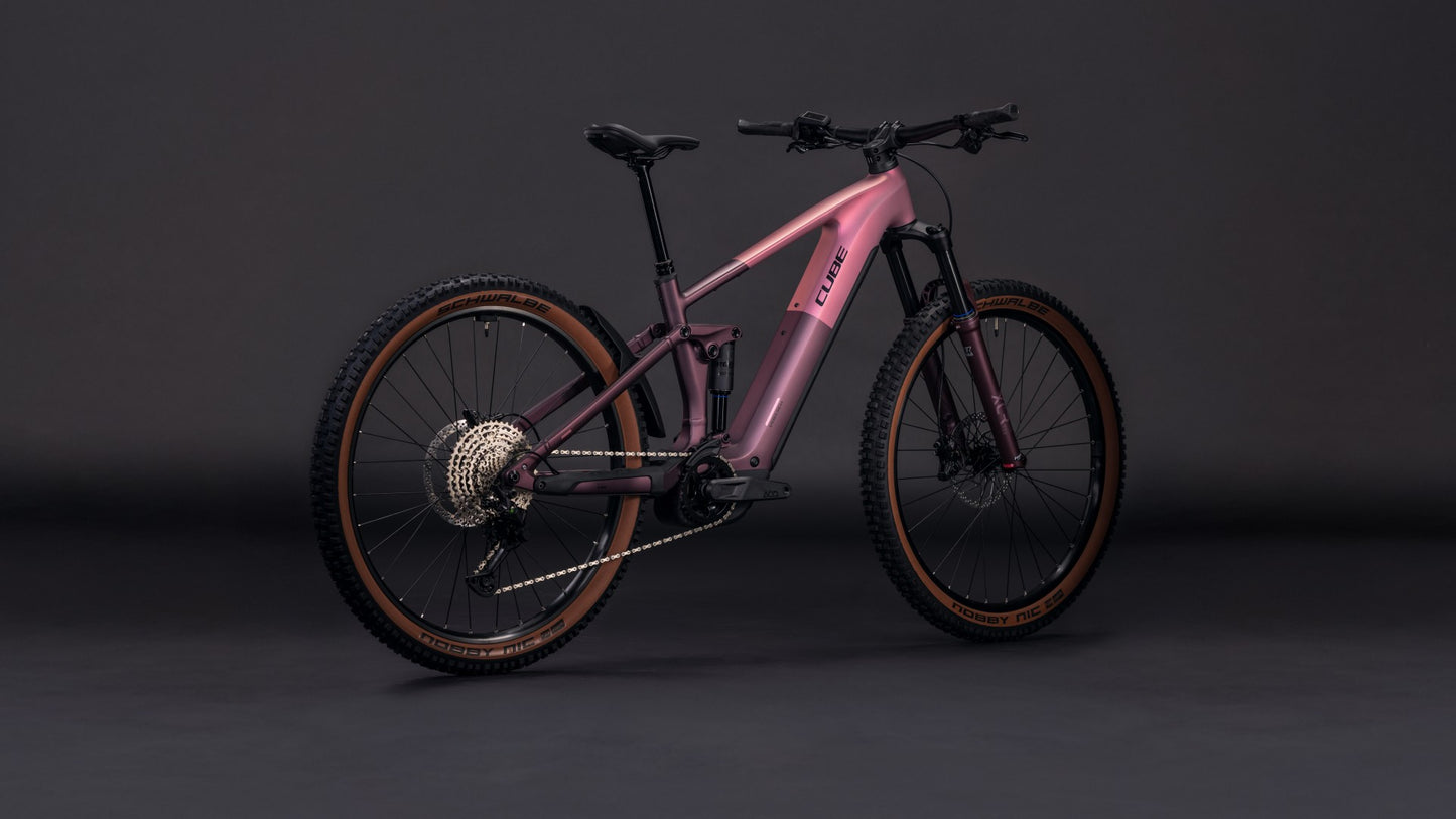 Das CUBE Stereo Hybrid ONE44 Pro 800 shiftblush'n'raisin 2026 Mountainbike mit mattrosa Lackierung, Shimano XT Schaltung, Federgabel und dicken Stollenreifen steht auf einem dunklen, nahtlosen Hintergrund.