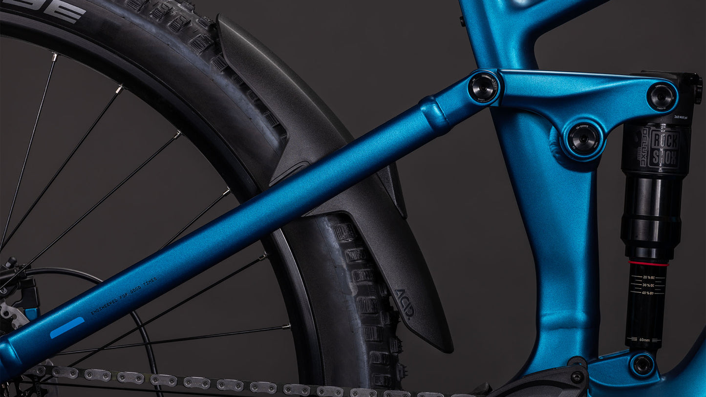Nahaufnahme des CUBE Stereo Hybrid ONE44 EX 800 electricblue'n'blue 2026 E-MTB-Rahmens mit Hinterradfederung, schwarzem Schutzblech, Reifen und einem Teil des Bosch CX Antriebssystems vor einem dunklen Hintergrund.