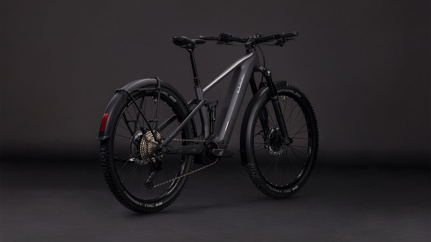 Das CUBE Stereo Hybrid ONE44 EXC 800 FE in irongrey'n'chrome (2026) ist ein E-Bike mit dicken Reifen, Scheibenbremsen, hinterem Schutzblech, sichtbarer Schaltung und einem leistungsstarken Bosch CX-Motor - dargestellt vor einem dunklen Studiohintergrund.