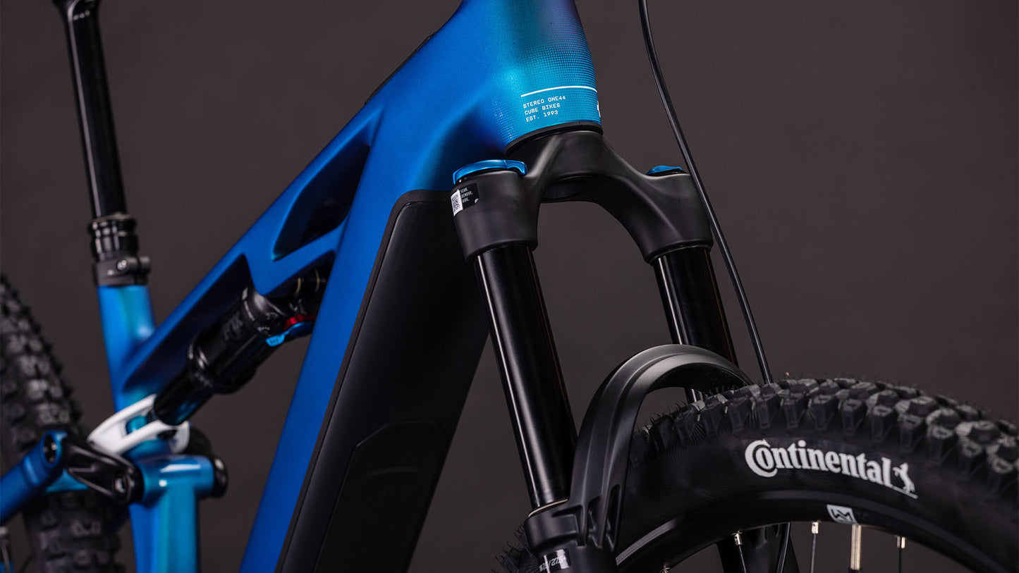 Nahaufnahme des CUBE Stereo Hybrid ONE44 HPC SLX 800 nebula'n'white 2026 mit Federgabel, Reifen mit Continental Branding und Rahmen. Mit Shimano XT Schaltung für reibungslose Schaltvorgänge vor einem dunklen, neutralen Hintergrund.