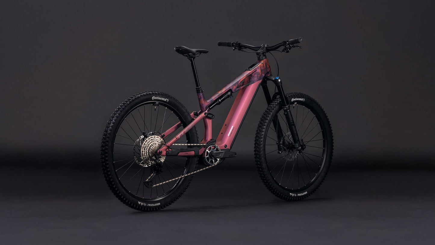 Das CUBE Stereo Hybrid ONE44 HPC SLX 800 shiftblush'n'art 2026 Elektro-Mountainbike hebt sich von einem dunklen Hintergrund ab, der den robusten Rahmen, die breite Bereifung und das fortschrittliche Federungssystem hervorhebt.
