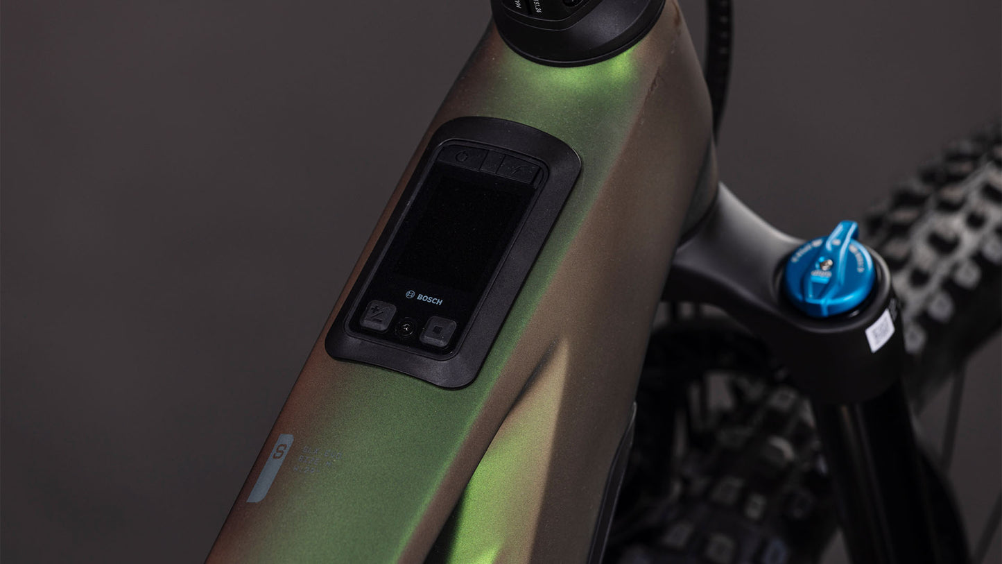 Nahaufnahme des Oberrohrs des CUBE Stereo Hybrid ONE44 HPC SLX Evo 800 stellar'n'grey 2026 mit integriertem Bosch-Display, grüner Metallic-Lackierung und Teilen des Shimano XT Di2-Antriebs sowie der Federgabel.