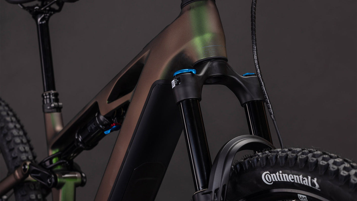 Nahaufnahme der vorderen Federgabel, des Rahmens und der Continental-Reifen des CUBE Stereo Hybrid ONE44 HPC SLX Evo 800 stellar'n'grey 2026 E-MTB vor einem dunklen Hintergrund. Schwarze und grüne Details heben die sichtbaren Federungskomponenten hervor.