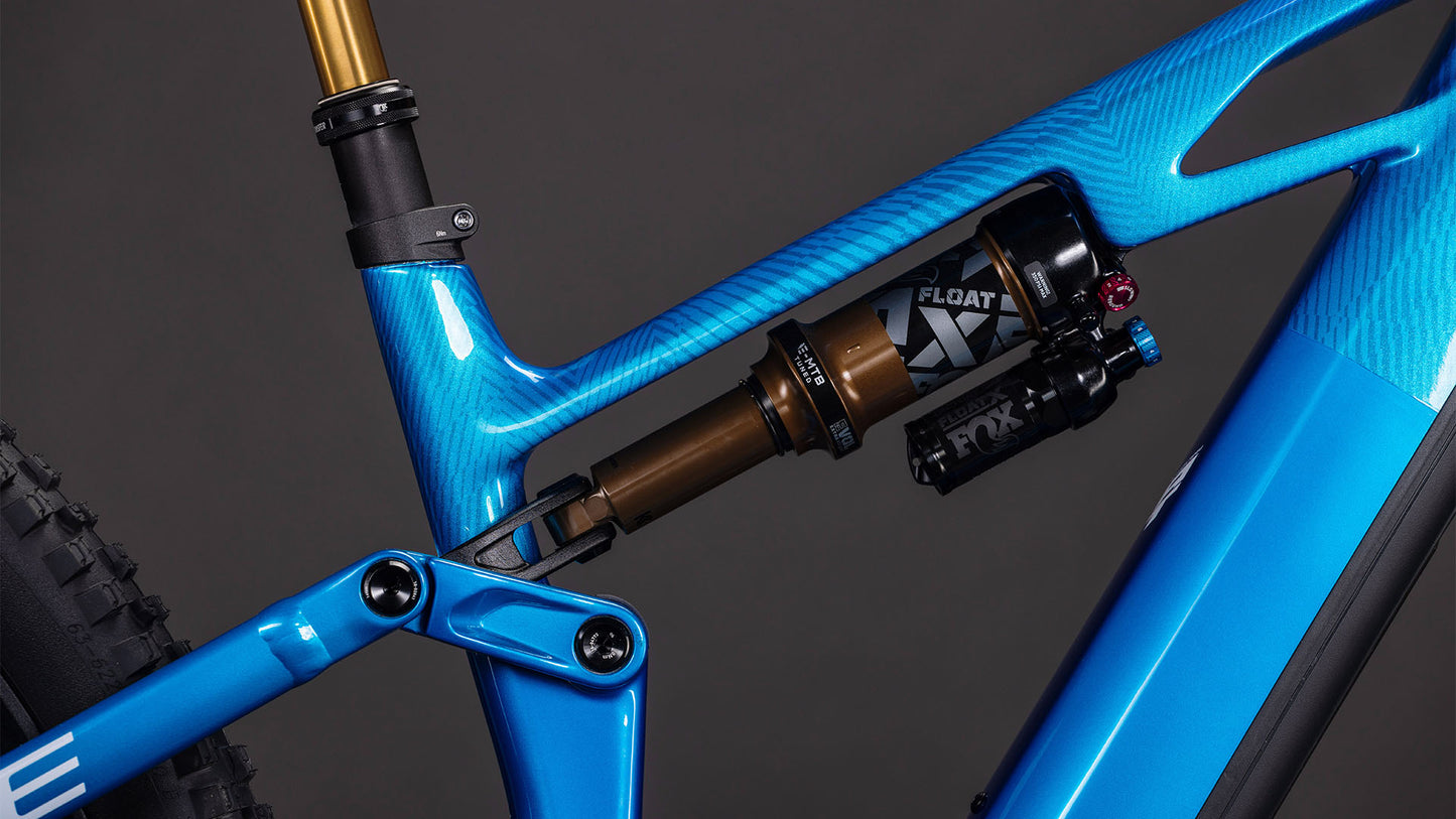 Nahaufnahme des blauen Mountainbike-Rahmens CUBE Stereo Hybrid ONE44 HPC AT 800 actionteam 2026 mit Hinterradfederung mit FOX Float X-Dämpfer, strukturierter Oberfläche und einem Teil des Hinterrads.
