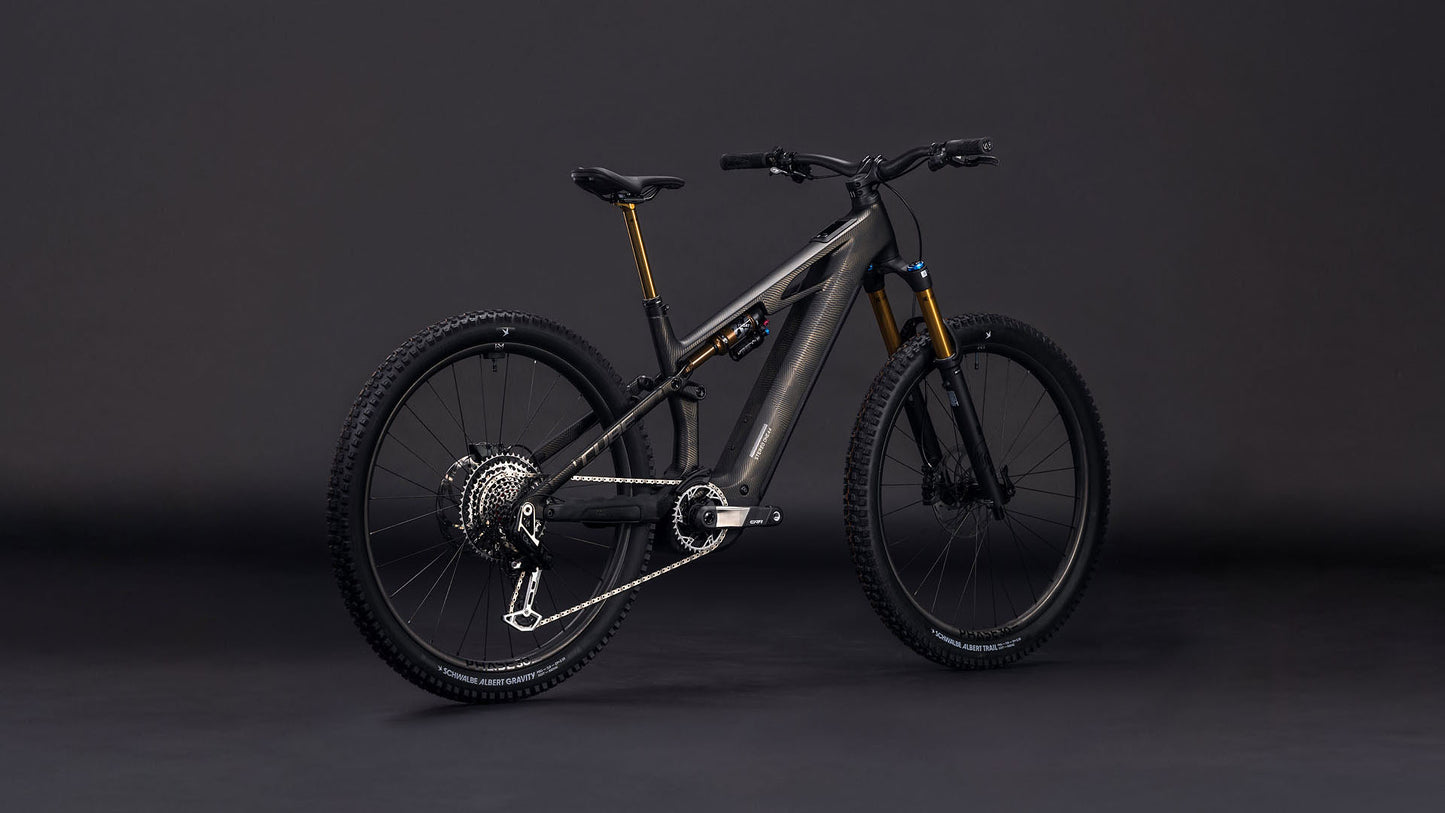Das CUBE Stereo Hybrid ONE44 HPC SLT 800 carbongrid'n'chrome 2026, ein modernes schwarzes All-Mountain E-Bike mit Vollfederung, dicken Reifen, goldener Vorderradgabel und einem leistungsstarken Bosch CX-R Motor, steht auf einem dunklen Hintergrund.