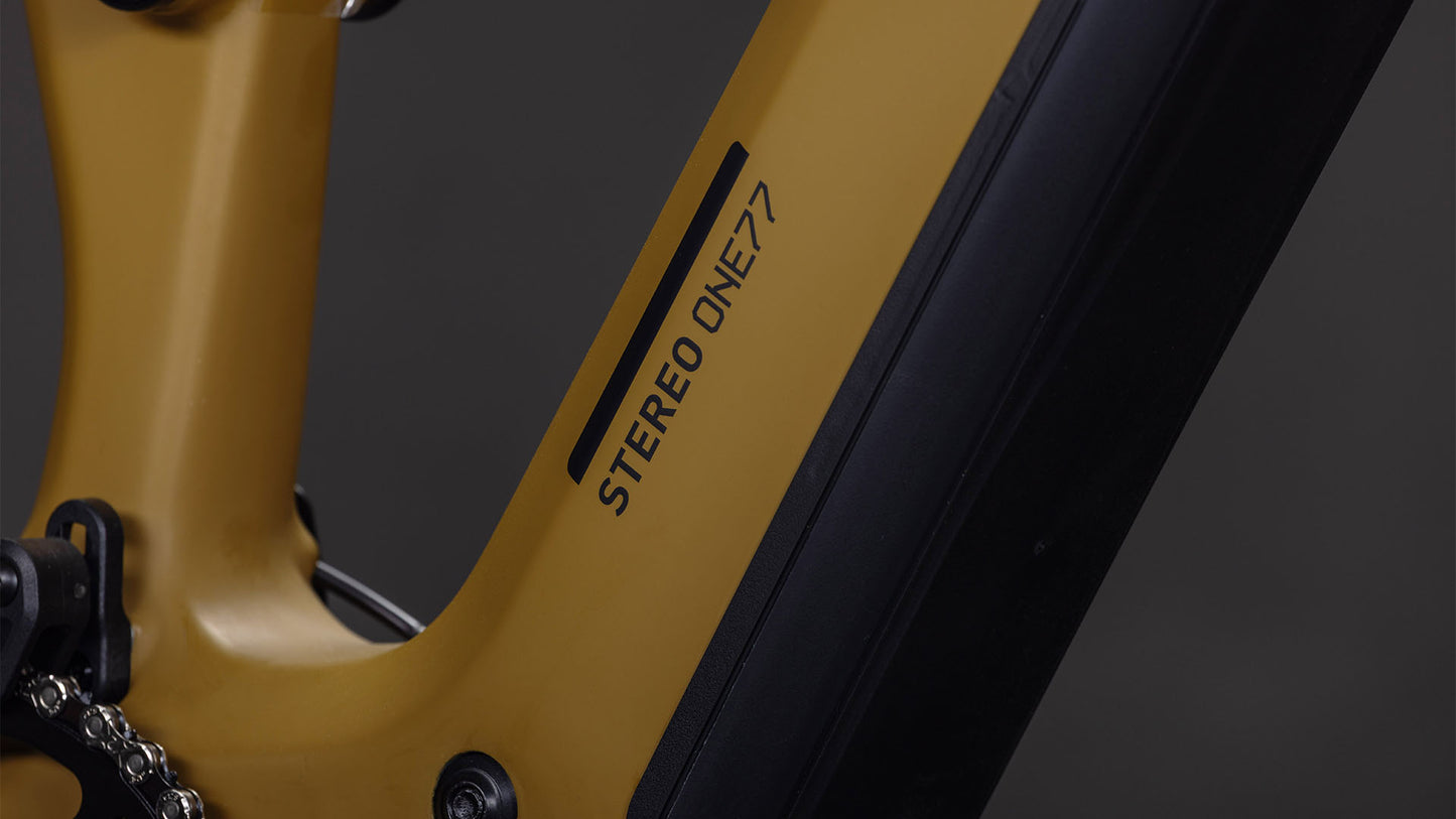 Nahaufnahme eines CUBE Stereo Hybrid ONE77 HPC Race 800 willowgreen'n'black 2026 Fahrradrahmens mit schwarzem Aufdruck "STEREO ONE77", der die Kette und Hardwarekomponenten zeigt.