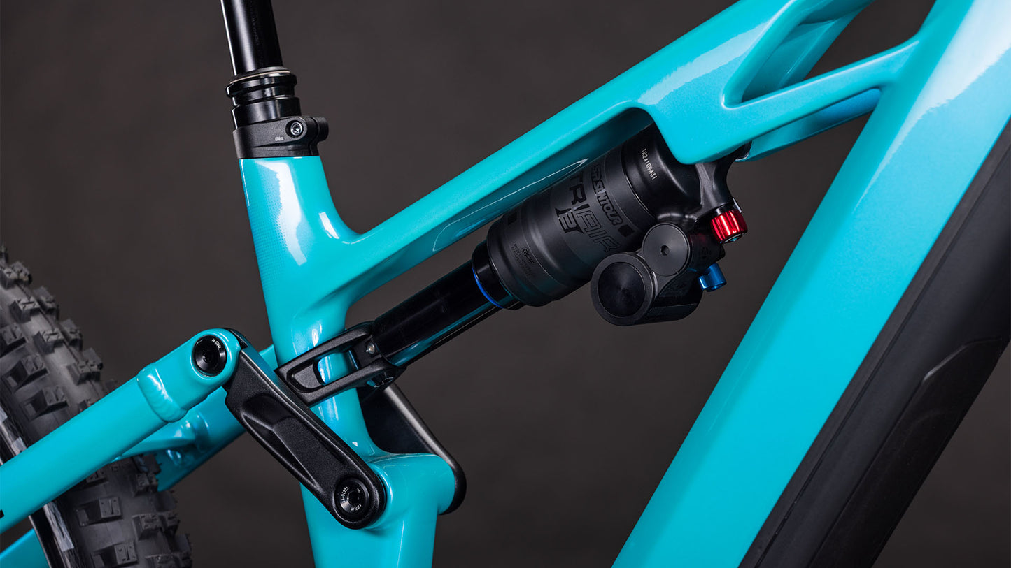 Nahaufnahme des CUBE Stereo Hybrid ONE77 HPC Race 800 swimmingpool'n'black 2026 Mountainbike-Rahmens, wobei die Hinterradfederung mit schwarzem Stoßdämpfer und Einstellknöpfen vor dunklem Hintergrund hervorgehoben wird.