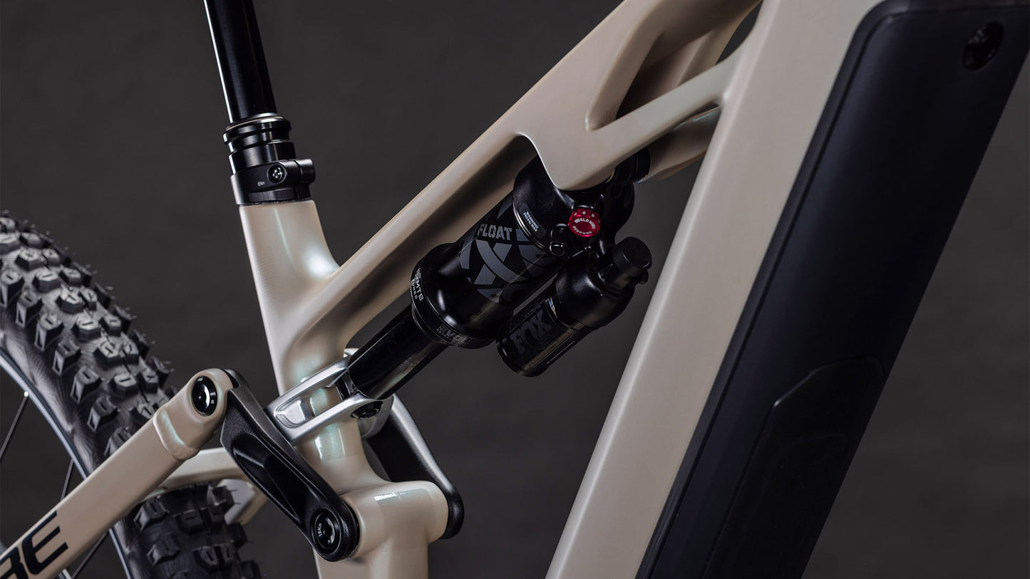 Nahaufnahme des CUBE Stereo Hybrid ONE77 HPC SLX 800 glintsand'n'black 2026 Rahmens. Hervorzuheben sind der hintere Stoßdämpfer und die Anlenkung mit 170 mm Federweg, das Hinterradprofil und eine sichtbare schwarze Batterie- oder Schutzabdeckung.