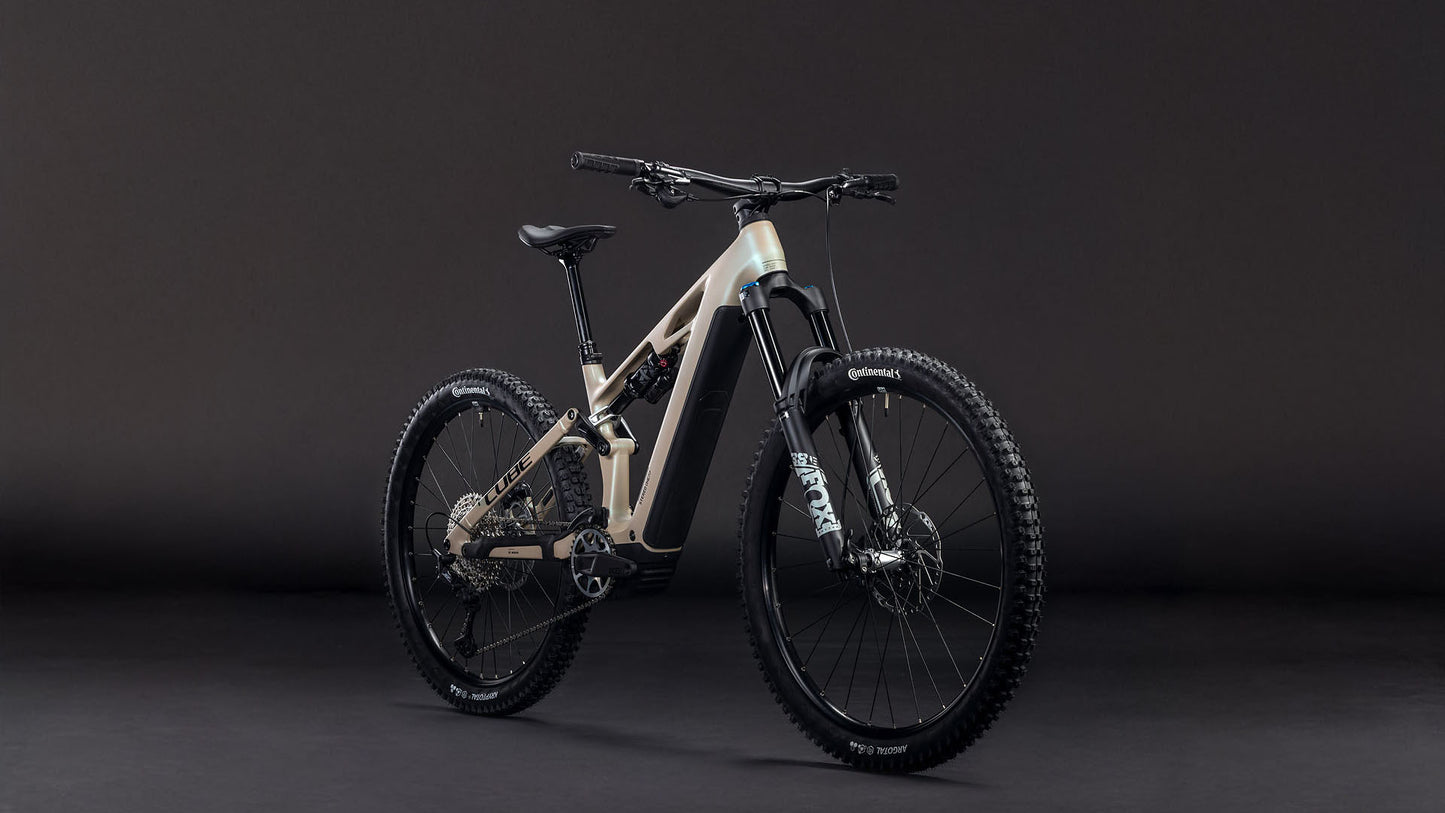 Das CUBE Stereo Hybrid ONE77 HPC SLX 800 glintsand'n'black 2026 ist ein modernes E-Mountainbike mit 170 mm Federweg, dicken Stollenreifen, einem hellen Rahmen und schwarzen Komponenten auf dunklem Grund.