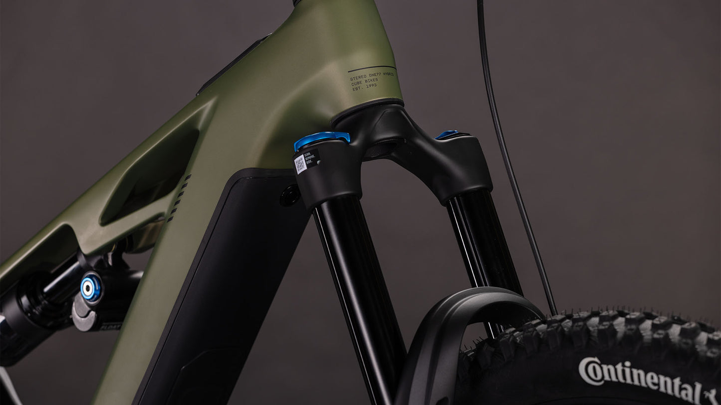 Nahaufnahme der Federgabel und des Rahmens des CUBE Stereo Hybrid ONE77 HPC TM 800 reedgreen'n'matrix 2026 E-MTB mit 170 mm Federweg, sichtbarem Stoßdämpfer und Continental-Reifen vor dunklem Hintergrund.