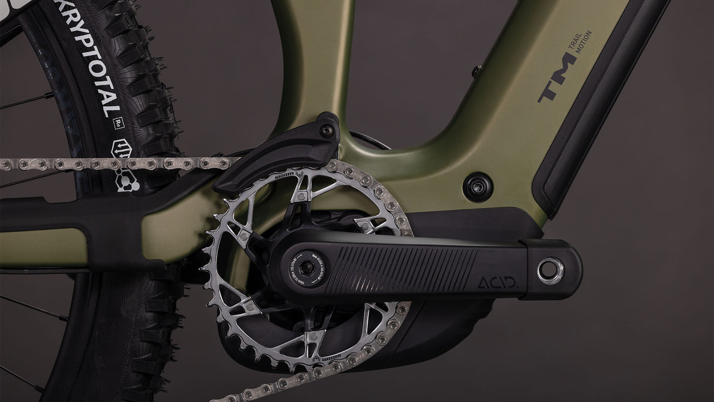 Nahaufnahme des Cube Stereo Hybrid ONE77 HPC TM 800 reedgreen'n'matrix 2026 von CUBE. Hervorzuheben sind die Kurbelgarnitur, das Kettenblatt, die Kette, der Pedalarm, der KRYPTOTAL-Hinterreifen, der schilfgrüne Rahmen mit schwarzen Akzenten und der leistungsstarke Bosch CX-Motor.