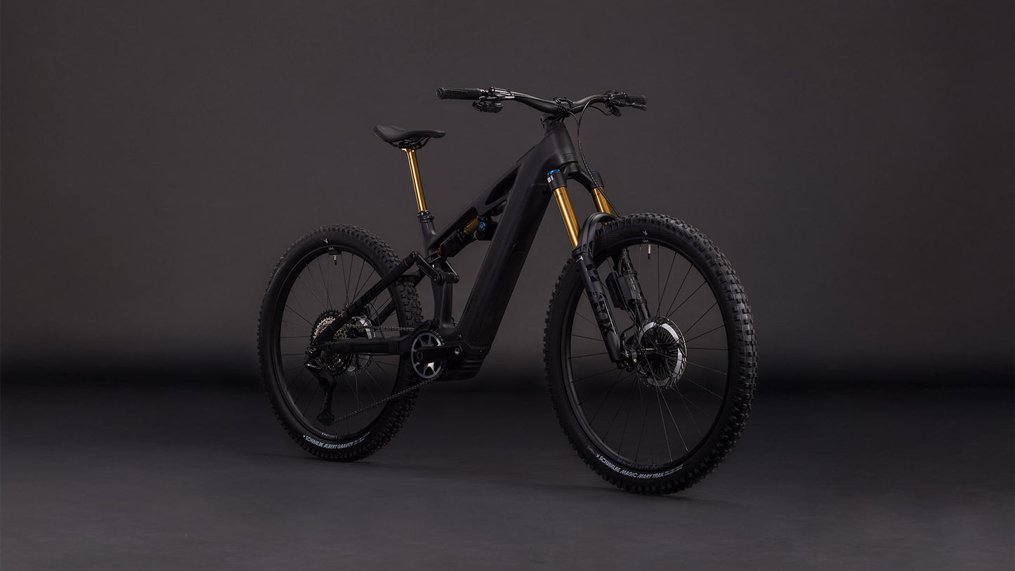 Das CUBE Stereo Hybrid ONE77 HPC AT 800 carbon'n'gold 2026 ist ein modernes schwarzes Elektro-Mountainbike mit Bosch CX-Motor, dicken Reifen, Federung vorne und hinten und goldfarbenen Gabeln, das vor einem schlichten dunklen Hintergrund gezeigt wird.