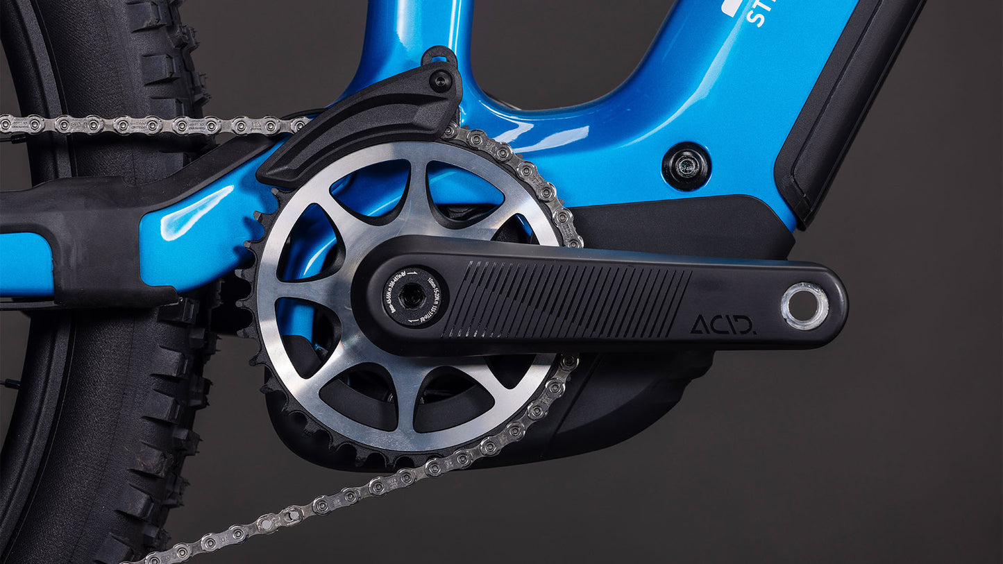 Nahaufnahme der Kurbelgarnitur, des Kettenblatts, des Pedals und der Kette des CUBE Stereo Hybrid ONE77 HPC AT 800 actionteam 2026 mit Shimano XT Di2-Komponenten vor einem dunklen Hintergrund, der die detaillierte Mechanik und Textur zeigt.