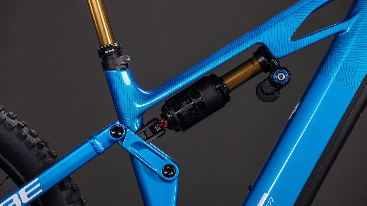 Nahaufnahme des blauen Rahmens des CUBE Stereo Hybrid ONE77 HPC AT 800 actionteam 2026 mit Hinterradfederung, fortschrittlichem Gestängesystem und Bosch CX-Motor vor einem dunklen Hintergrund.
