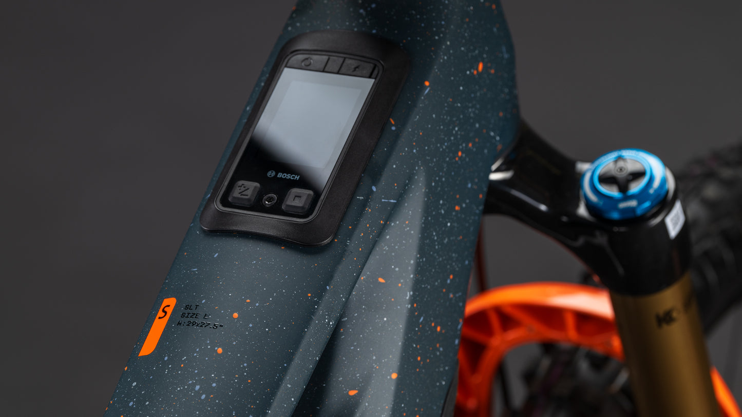 Nahaufnahme des CUBE Stereo Hybrid ONE77 HPC SLT 800 galaxy'n'orange 2026 Rahmens mit digitalem Bosch-Display, Tasten und gesprenkeltem Lack mit orangefarbenen Highlights - angetrieben vom Bosch CX-R Motor.