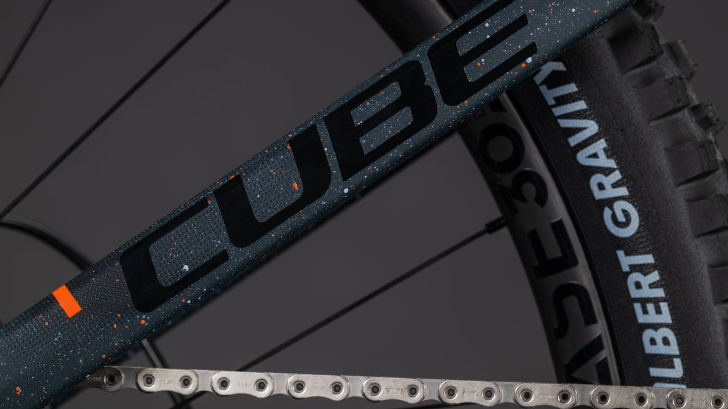 Nahaufnahme des CUBE Stereo Hybrid ONE77 HPC SLT 800 galaxy'n'orange 2026 Rahmens, der Big-Mountain-Performance mit SCHWALBE G-ONE RACE 50 Reifen und Kette zeigt - gebaut für kraftvolle Fahrten.