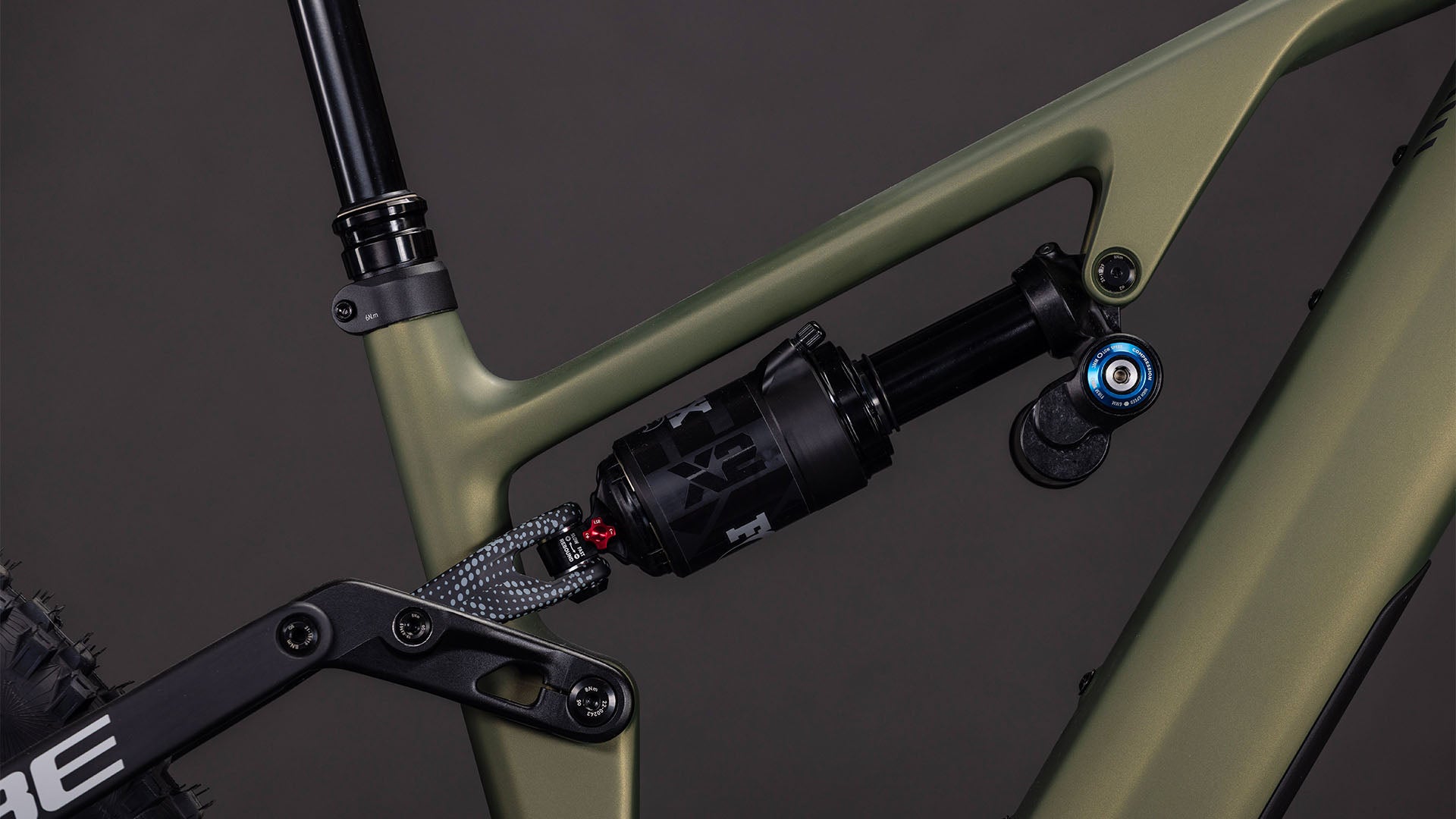 Nahaufnahme des hinteren Federungssystems mit schwarzem Stoßdämpfer an einem CUBE AMS Hybrid 177 C:62 TM 600X reedgreen'n'matrix 2026 Rahmen mit schwarzer Anlenkung vor dunklem Hintergrund.