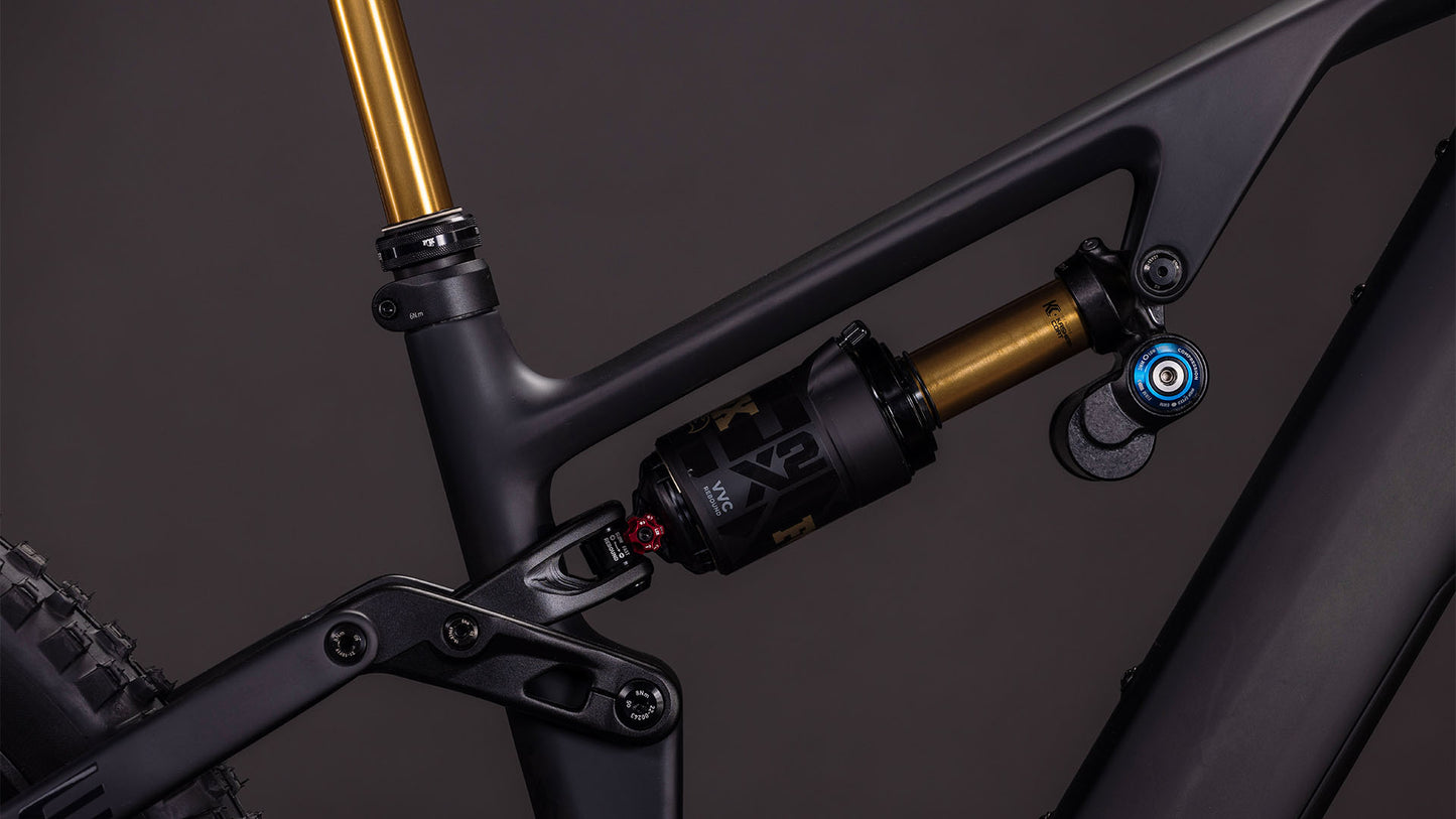Nahaufnahme der Hinterradaufhängung des CUBE AMS Hybrid 177 C:62 AT 600X carbon'n'gold 2026, wobei der gold-schwarze Stoßdämpfer auf einem mattschwarzen Carbonrahmen mit sichtbaren Anlenkungselementen ins Auge fällt.