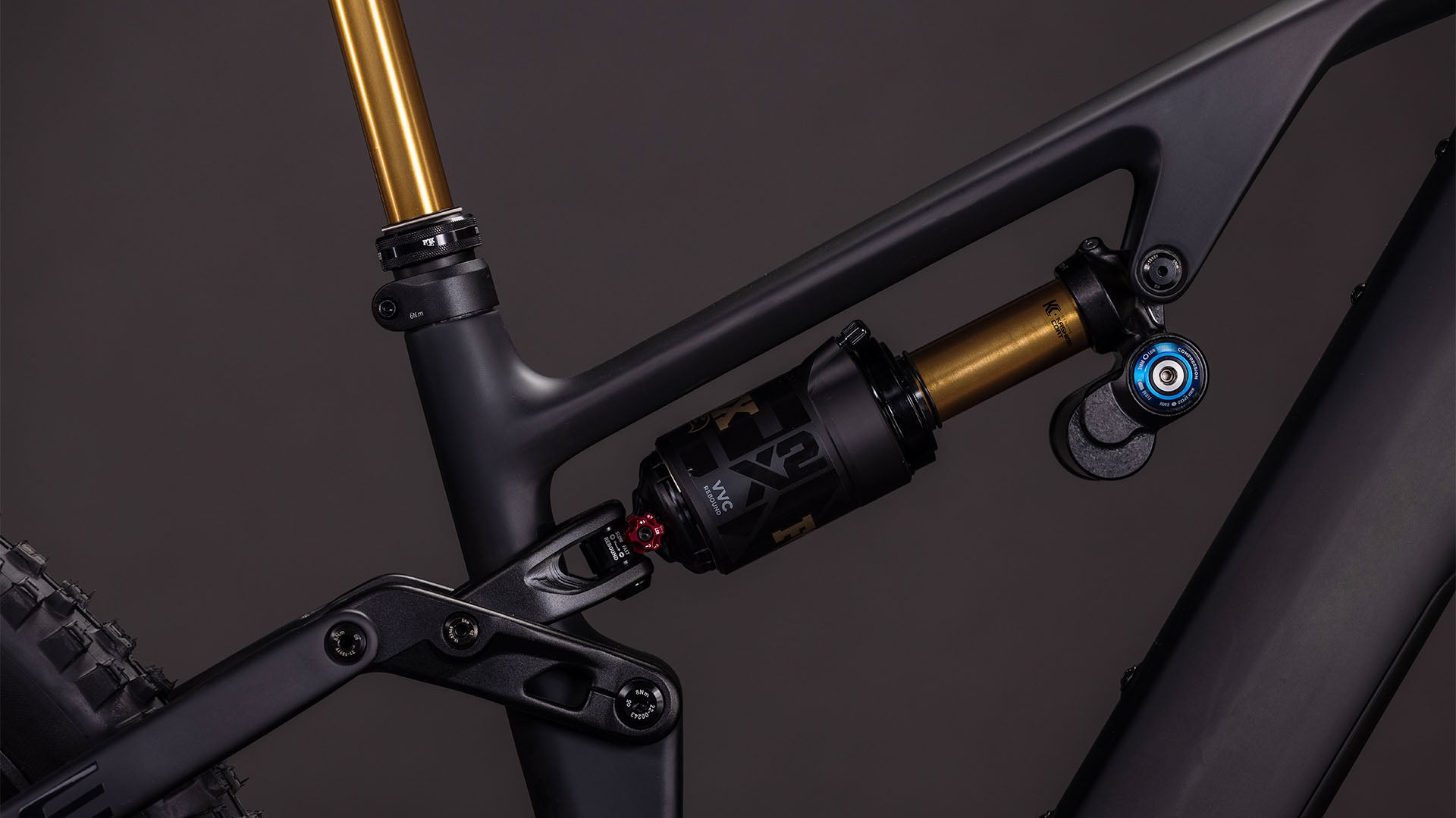 Nahaufnahme der Hinterradaufhängung des CUBE AMS Hybrid 177 C:62 AT 600X carbon'n'gold 2026, wobei der gold-schwarze Stoßdämpfer auf einem mattschwarzen Carbonrahmen mit sichtbaren Anlenkungselementen ins Auge fällt.