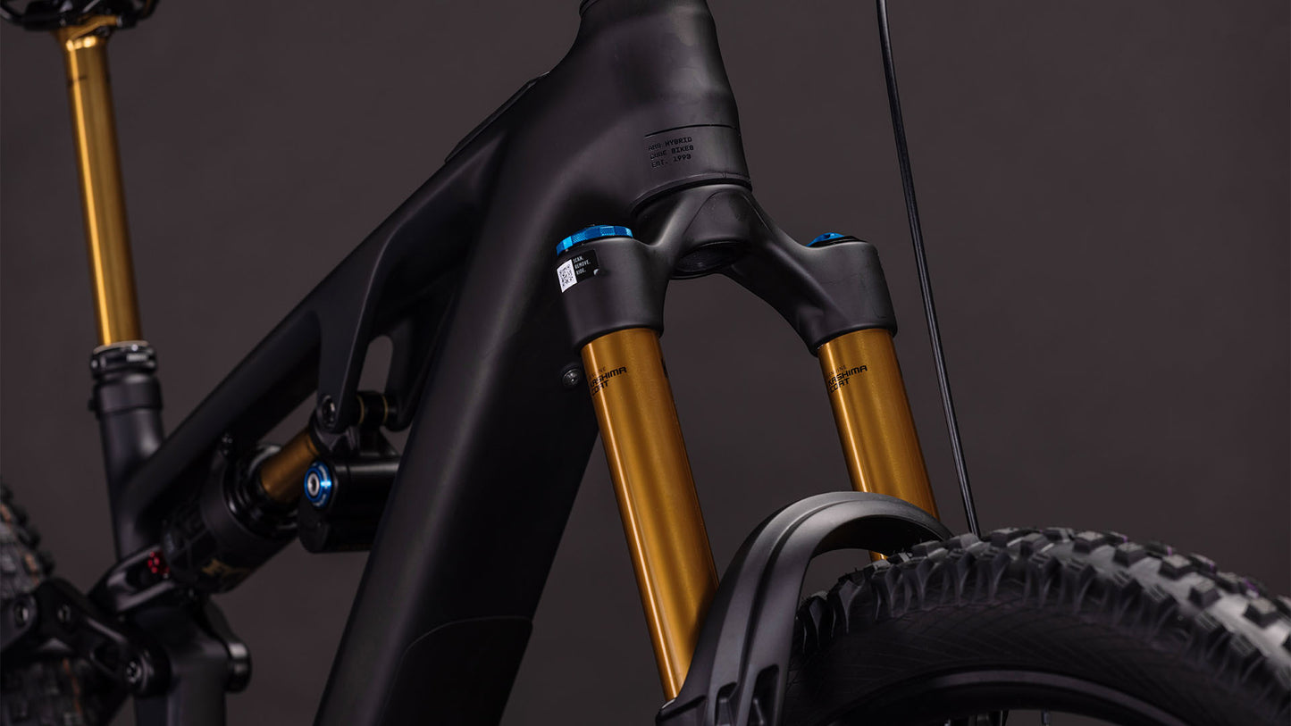 Die Nahaufnahme des CUBE AMS Hybrid 177 C:62 AT 600X carbon'n'gold 2026 zeigt den mattschwarzen Carbonrahmen, die goldfarbenen Standrohre und die integrierten Bosch CX-R Motor-Details vor dunklem Hintergrund.