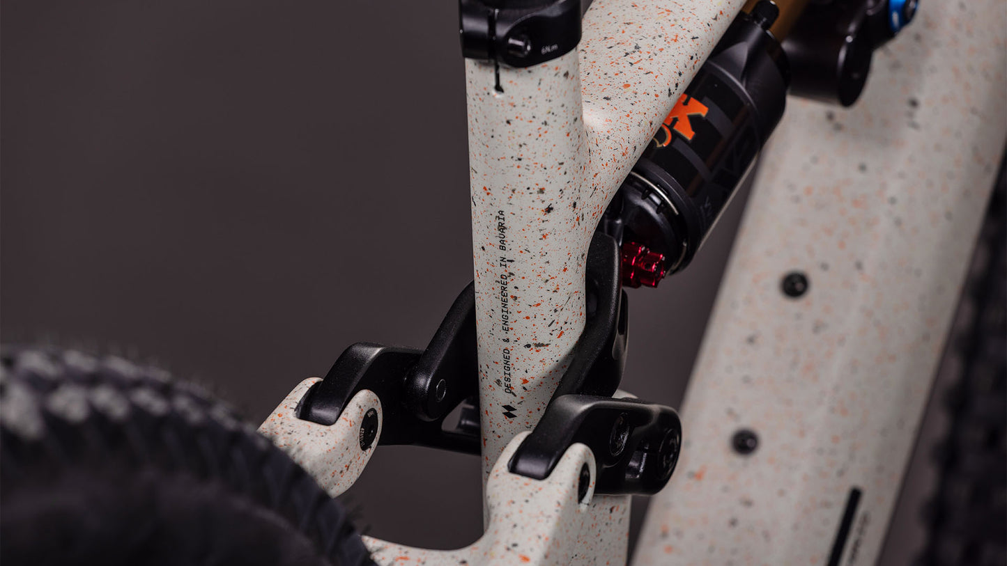 Nahaufnahme des CUBE AMS Hybrid 177 C:62 SUPER TM 600X in reedbeigegrit'n'orange, mit 170 mm Federweg-Hinterbau und Sram XX Eagle-Getriebe vor dunklem Hintergrund.