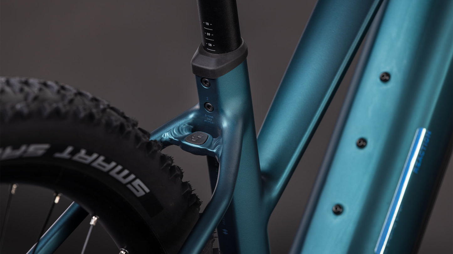Nahaufnahme des CUBE Reaction Hybrid ONE 800 in royalgreen'n'prism Trapeze 2026, die das Sitzrohr, den Hinterreifen mit SMART SAM-Branding, einen Teil des Unterrohrs und ein leistungsstarkes Bosch-Motorsystem vor einem unscharfen Hintergrund zeigt.