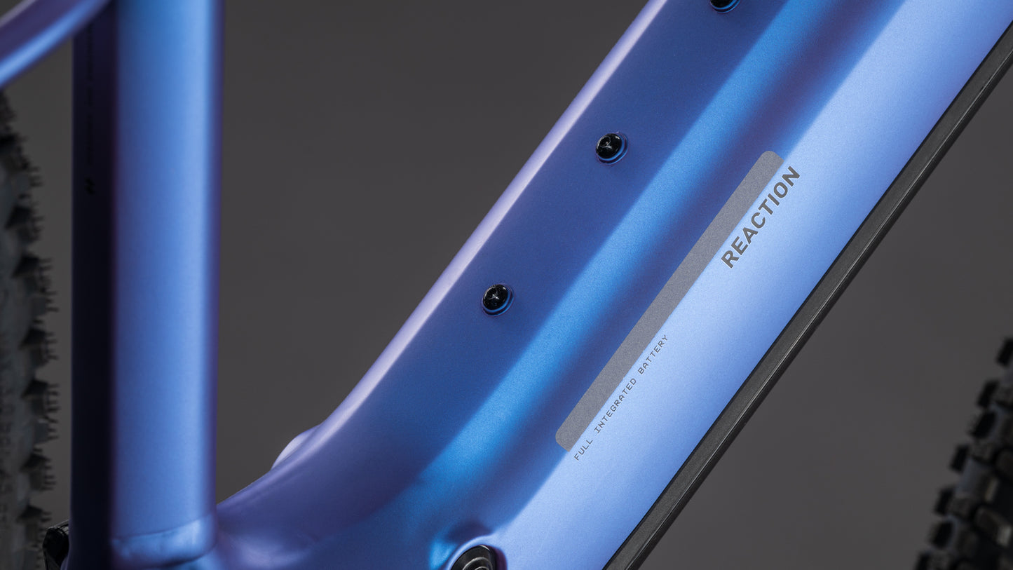 Nahaufnahme des CUBE Reaction Hybrid ONE 800 blueiris'n'reflect 2026 Rahmens, mit "REACTION" und "FULLY INTEGRATED BATTERY" auf dem Schlauch, sowie einem Teil des Reifens und einem Blick auf den leistungsstarken 800 Wh Akku auf der linken Seite.