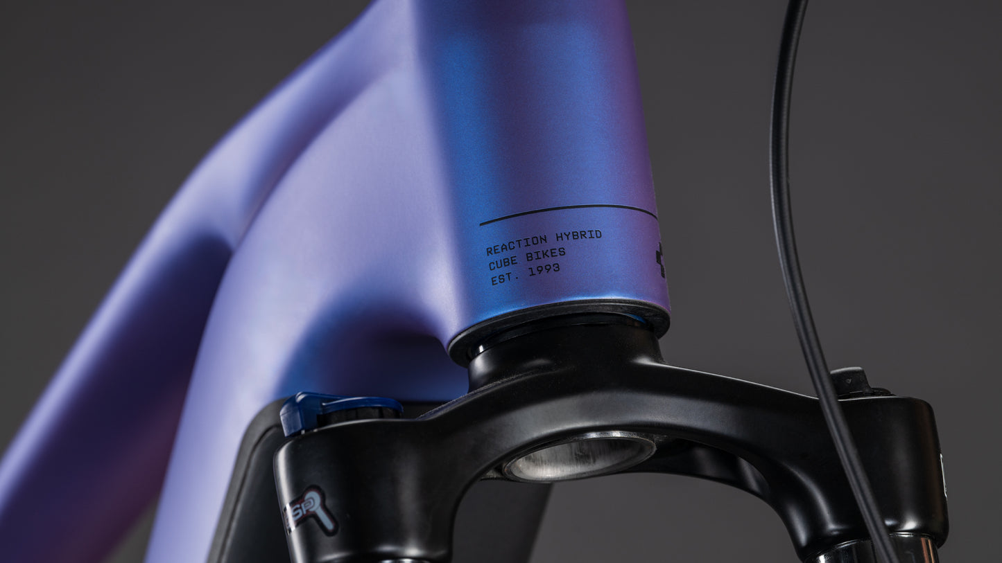 Nahaufnahme des CUBE Reaction Hybrid ONE 800 in blueiris'n'reflect, die den matten Farbverlauf des Rahmens mit der Aufschrift "REACTION HYBRID CUBE BIKES EST. 1993" und einem leistungsstarken Bosch-Motor für nahtlose, mühelose Fahrten.