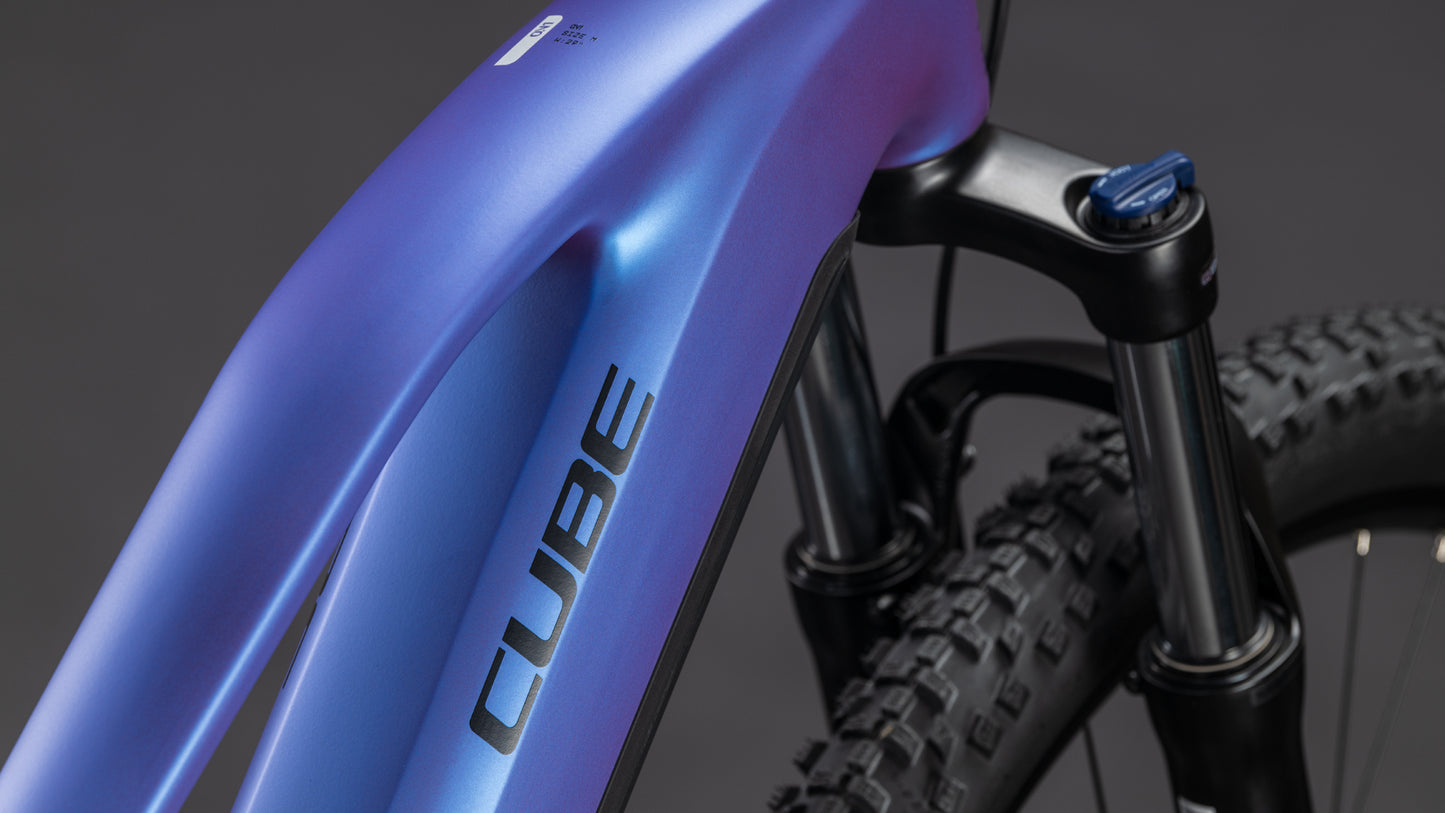 Nahaufnahme der Frontpartie des CUBE Reaction Hybrid ONE 800 blueiris'n'reflect Trapeze 2026 E-Bike, die den Rahmen, den Bosch-Motor und die Federgabel vor einem dunklen Hintergrund zeigt.