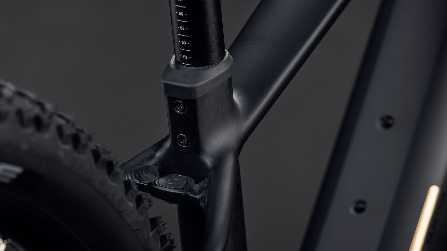 Die Nahaufnahme des CUBE Reaction Hybrid Pro 800 blackline 2026 zeigt den mattschwarzen Rahmen, die Sattelstütze und den hinteren Noppenreifen. Zur Ausstattung gehören ein 800-Wh-Akku und ein leistungsstarker Bosch CX-Antrieb, alles vor einem dunklen Hintergrund.