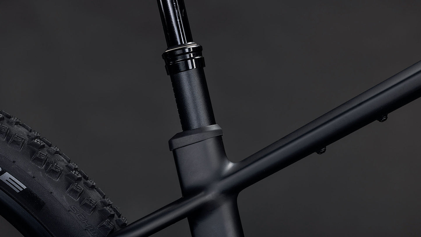 Nahaufnahme des CUBE Reaction Hybrid Pro 800 blackline 2026 Rahmens mit der mattschwarzen Sattelstütze, dem Hinterrad und dem Oberrohr. Vor dem dunklen Hintergrund ist ein Bosch CX Motor zu sehen.